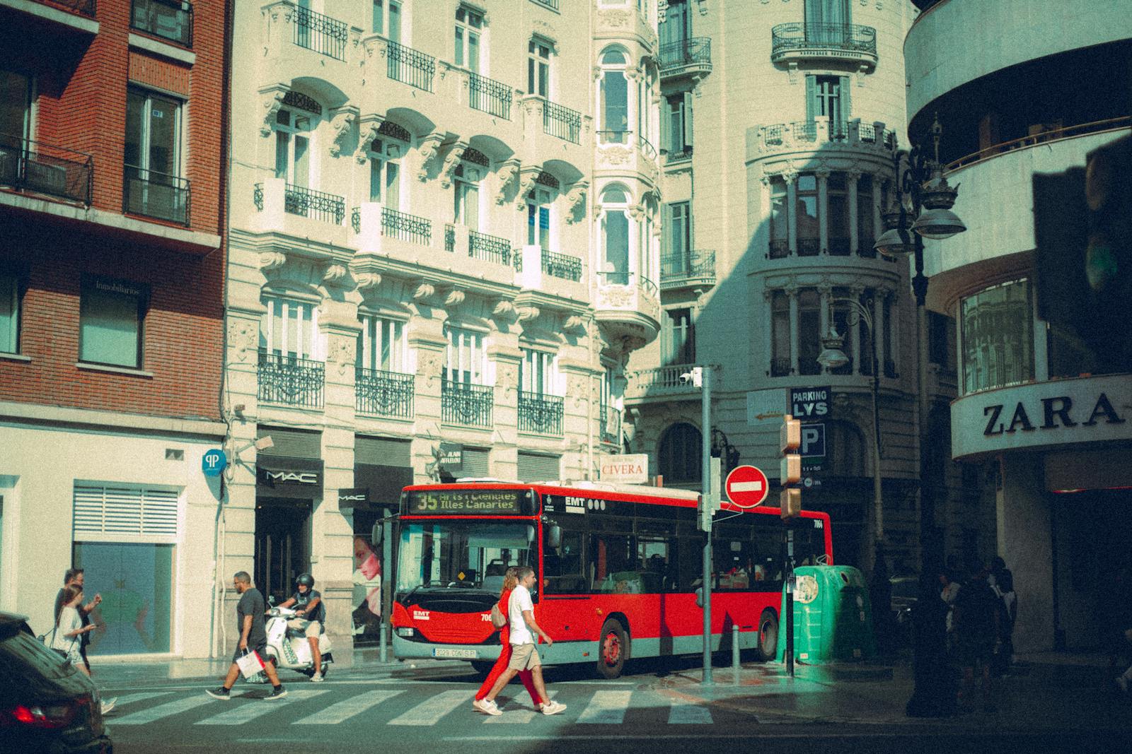 Red EMT city bus at busy crosswalk in Madrid