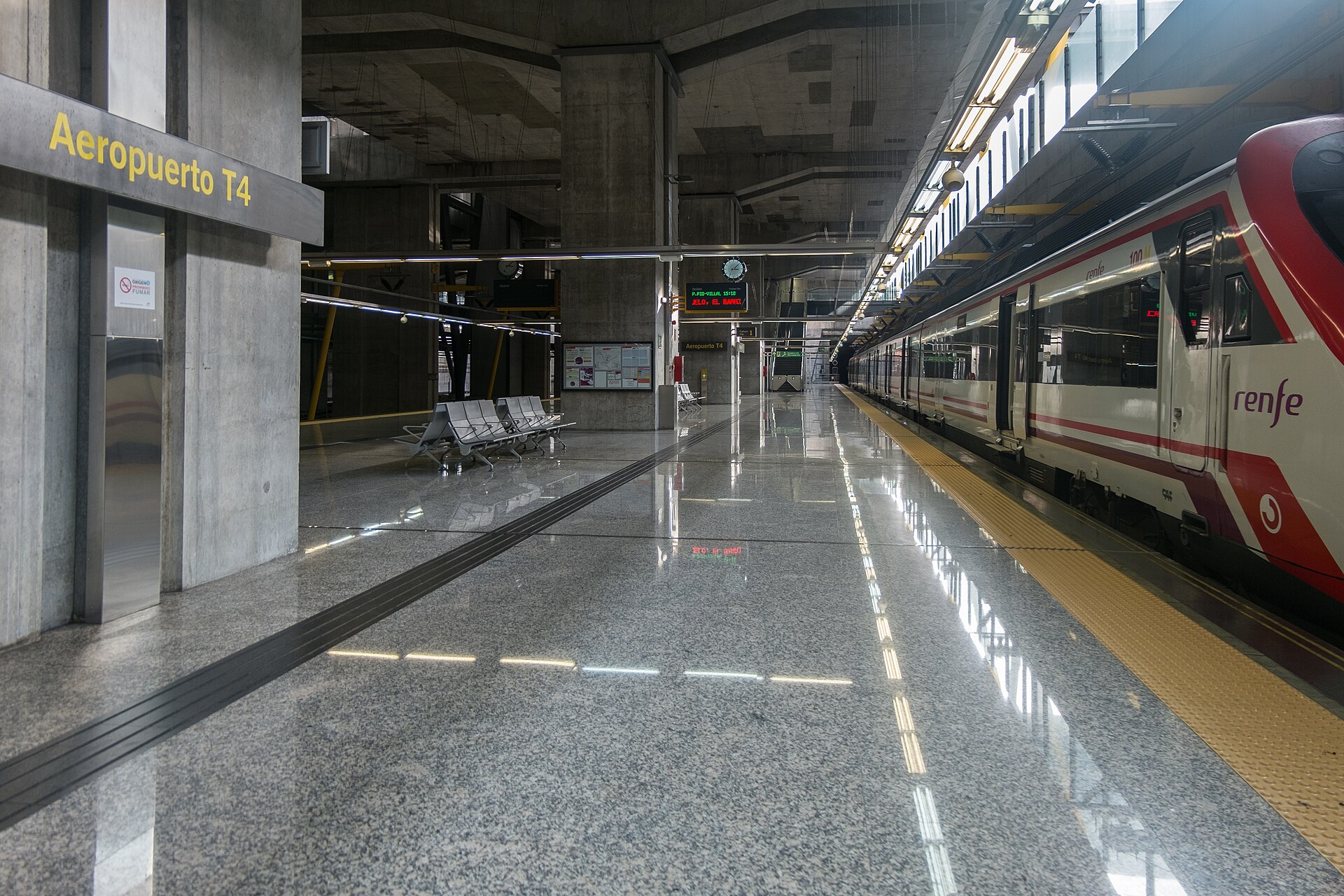 A Layover in Madrid: What to Do With 4, 6, 8 or 12 Hours 2 A red and white Renfe Cercanías train waiting at the underground Aeropuerto T4 station, with a polished granite platform and a yellow station sign