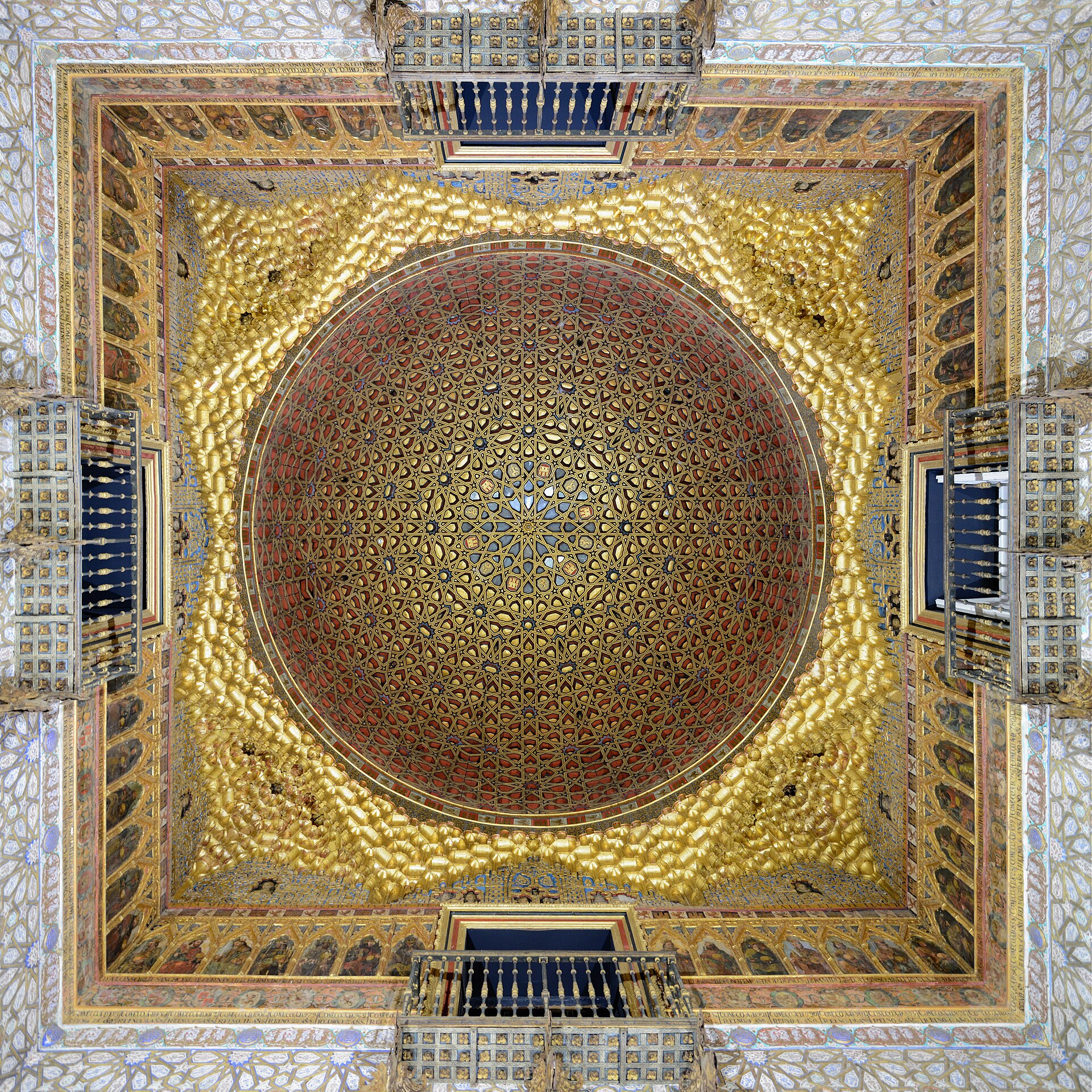 Looking straight up into a gilded wooden dome with an interlaced star pattern, framed by small balconies on four sides